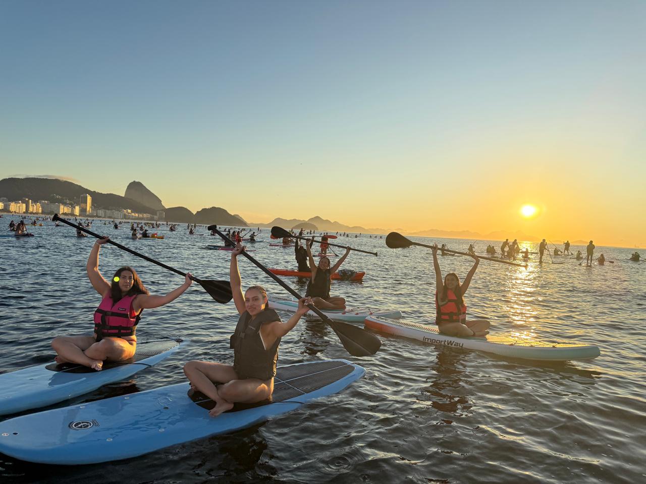Grupo erguendo os remos no nascer do sol em Copacabana
